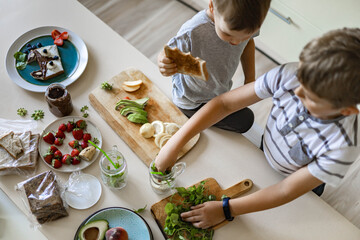 Top view children cooking fresh healthy breakfast with fruit, berries, vegetables on table kitchen