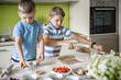 © kostikovanata - Two funny brothers cooking homemade summer dessert preparing dough and slicing ingredients