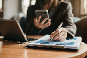 Business documents on office desk with laptop and smart phone and graph business diagram and women working at office in the morning.