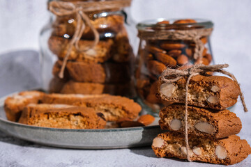 Traditional Italian cantuccini cookies with almonds in glass jar. Sweet dried biscuits. Homemade fresh Italian cookies cantuccini stacks and organic almond seeds. Healthy organic eating