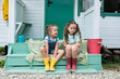 © tgordievskaya - Life in the suburbs. Siblings sitting  on porch at backyard against house. Kids relaxing on steps and talking to each other. Childhood concept