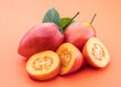 © volff - Ripe tamarillo fruits with slices and tamarillo leaves isolated on a orange background.