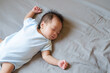 © Thannaree - Asian baby sleeping on gray bed