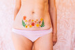© Westend61 - Woman in underwear showing Caesarean scar with flowers tattoo