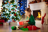 Fototapeta Na ścianę - Kids at Christmas tree. Children open presents