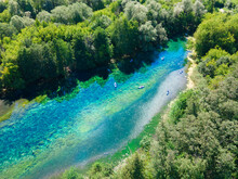 Summer Vacation On A Winding Forest River. People Are Paddling In The Blue Lagoon. Pure Clear Water Glistens In The Sun's Rays. The Banks Of The Reservoir Are Overgrown With Dense Forest.