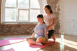 Young woman with down syndrome doing exercise with yoga teacher indoors