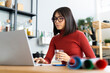 © Westend61 - Businesswoman working on laptop holding water glass at home office