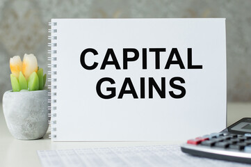 Capital Gains. Business concept. Text on white notepad paper on light background