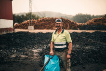 Smiling Worker With Plastic Bag And Tool Standing At Coal Factory