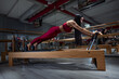 © Oleg - Pilates. Athletic Woman Exercising and Stretching on Gym Equipment