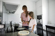 © Westend61 - Daughter learning to cook from mother in kitchen
