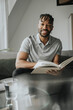 © Westend61 - Smiling man holding book on sofa at home