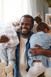 © Seventyfour - Vertical portrait of happy African-American father having fun with two cute daughters at home