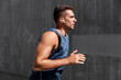 © Syda Productions - fitness, sport, training and lifestyle concept - young man in earphones running outdoors