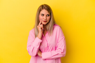 Young russian woman isolated on yellow background contemplating, planning a strategy, thinking about the way of a business.