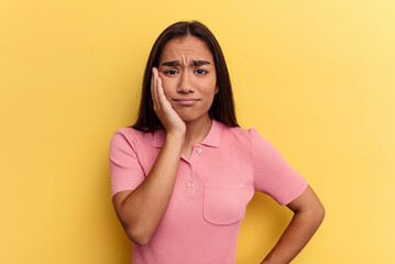 Wall Mural - Young mixed race woman isolated on yellow background who feels sad and pensive, looking at copy space.