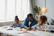 © Seventyfour - Portrait of loving African-American father with two girls drawing together in cozy home, copy space