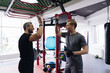 © diignat - Fit man discussing workout plan with his trainer, personal coach before starting workout in the gym. Personal coach standing near young man give hi five