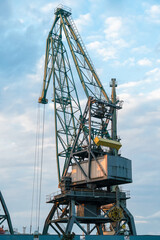 Close-up of a port crane against a beautiful blue sky with clouds before sunset. Cargo terminal. Batumi, Georgia. Vertical photo