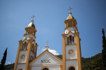 yellow and white catholic church towers, blue sky in the background