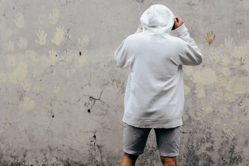 Wall Mural - Back View Hoodie Mockup of a Man standing facing the wall