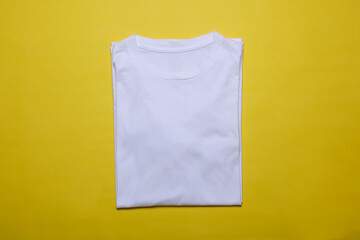 Wall Mural - Folded white t-shirt mockup on yellow background. Flat lay tee template