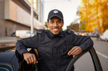 Police Officer In Uniform Poses At The Patrol Car
