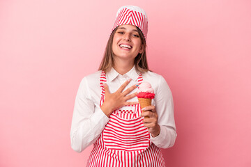 Wall Mural - Young ice cream maker woman holding ice cream isolated on pink background laughs out loudly keeping hand on chest.