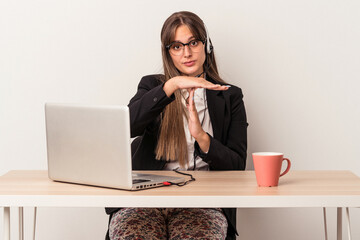 Wall Mural - Young caucasian woman doing telecommuting isolated on white background showing a timeout gesture.