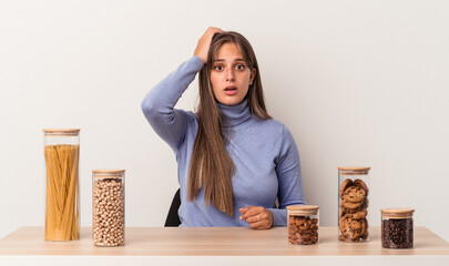 Wall Mural - Young caucasian woman sitting at a table with food pot isolated on white background being shocked, she has remembered important meeting.