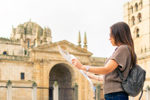 Young Caucasian Woman Using A Map With The Medieval Cathedral Of Zamora In The Background.