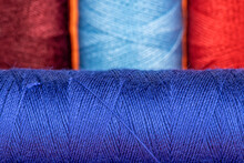 Four Bobbins Of Sewing Thread Of Blue And Red Shades