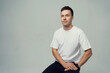 © muse studio - A man smiles looks at the camera in the studio and poses in a white T-shirt