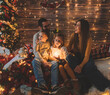Young parenthood. Hispanic family having a pleasant time with their baby and daughter in living room decorated by christmas tree and. Portrait loving family holiday. Merry xmas and Happy New Year.
