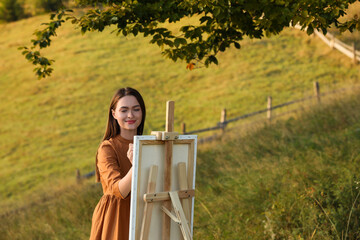 Poster - Beautiful young woman drawing on canvas in nature