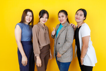 Four beautiful young Asian women smile and happily stand together as friendship and girl group wearing different casual outfits