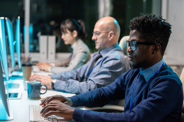 Sticker - Row of contemporary intercultural programmers working over new software in front of computer monitors in office