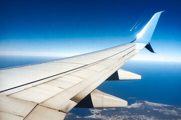 Wall Mural - wing of an airplane flying above the land