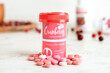 Bottle with healthy cranberry pills on light background