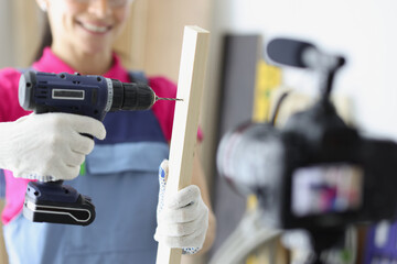 Wall Mural - Happy woman construction site worker use drill to make hole in wooden plank