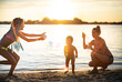 © YouraPechkin - Brother and sister play with their mom blowing bubbles on the lake