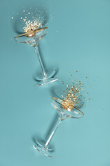 Two champagne glasses with splash of confetti over creative background