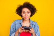 © deagreez - Photo of young worried young dark skin woman hold hands joystick play game isolated on yellow color background