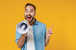 Young expressive happy man 20s wearing blue shirt white t-shirt hold scream in megaphone announces discounts sale Hurry up point finger aside on workspace isolated on plain yellow background studio.