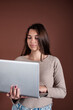 © Denis - Beautiful woman with a laptop in her hands on a brown background. Business lady works online.