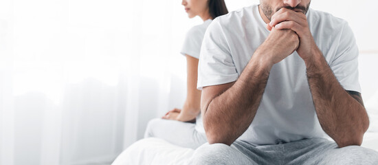 Cropped depressed millennial european male sits on bed, ignores offended sad female in bedroom interior