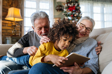 Wall Mural - Portrait of happy grandparents with little girl using digital tablet at home