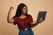 Emotional young black woman enjoying her new modern laptop