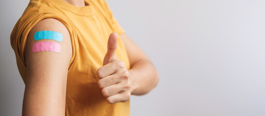 woman showing Thumb sign with bandage after receiving covid 19 vaccine. Vaccination, herd immunity, side effect, booster dose, vaccine passport and Coronavirus pandemic